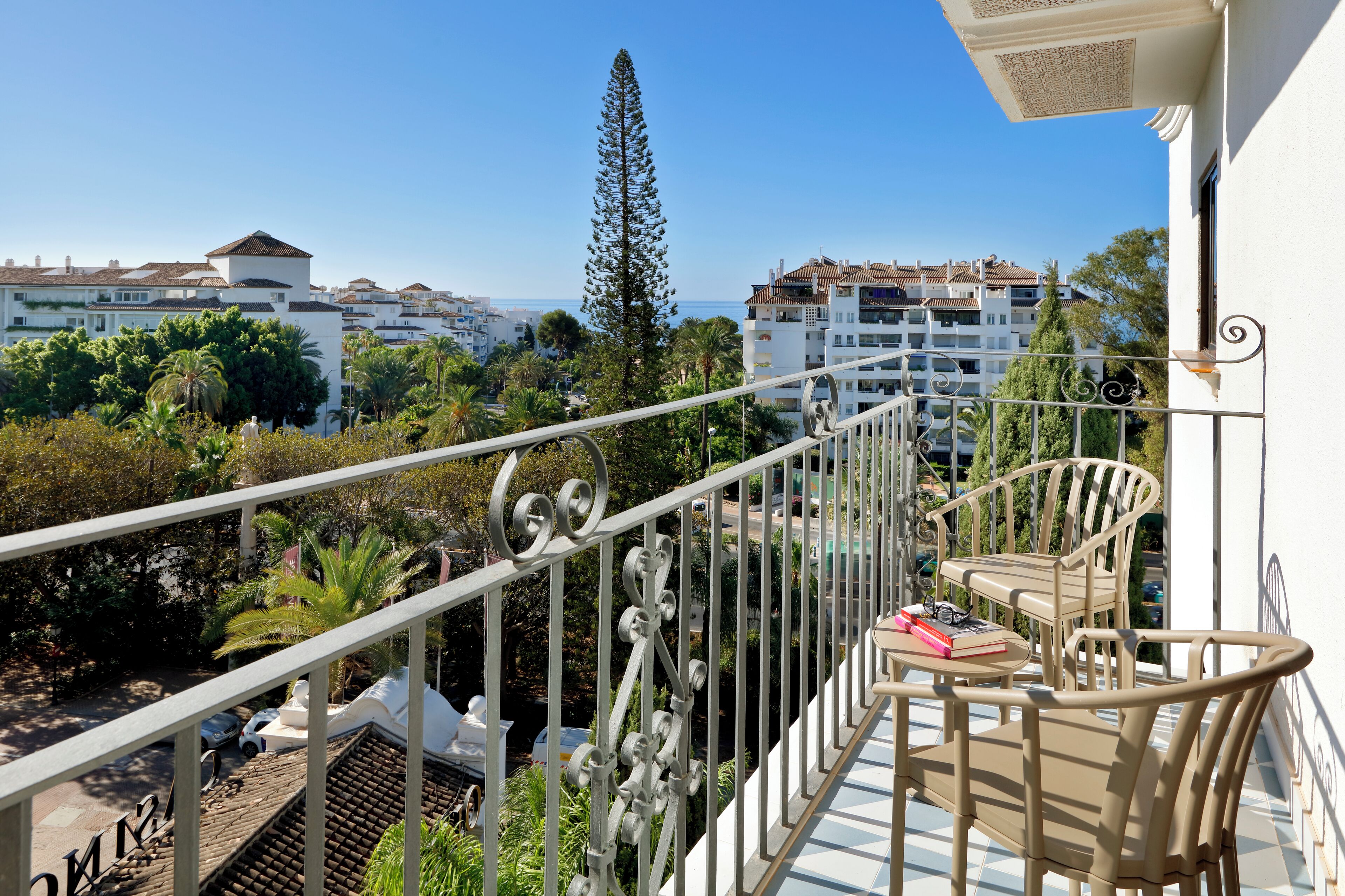 A balcony with a view of the sea and surrounding buildings.