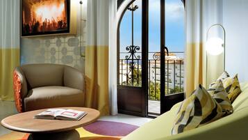 A modern hotel room with a sofa, armchair, and a table with a magazine.