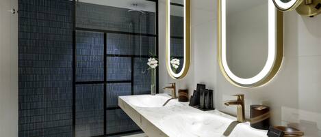 Un baño moderno con un espejo grande, dos lavamanos y una zona de ducha.