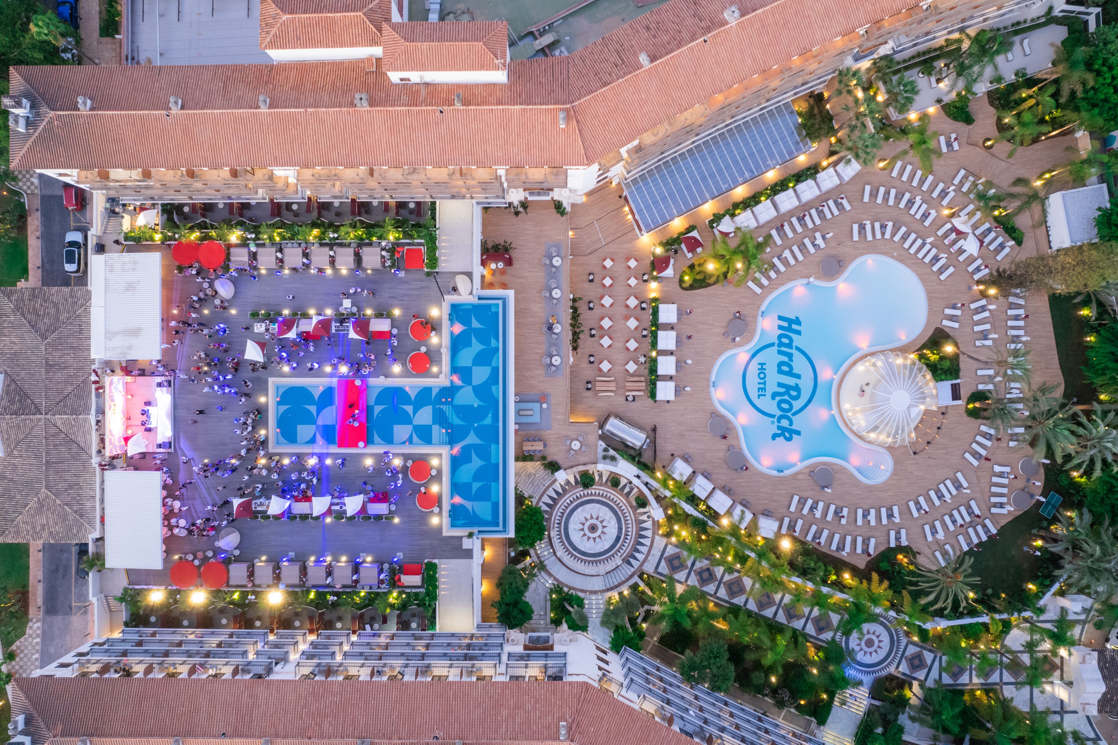 An aerial view of a hotel with a central pool area, multiple lounge areas, and a prominent Hard Rock Hotel sign.