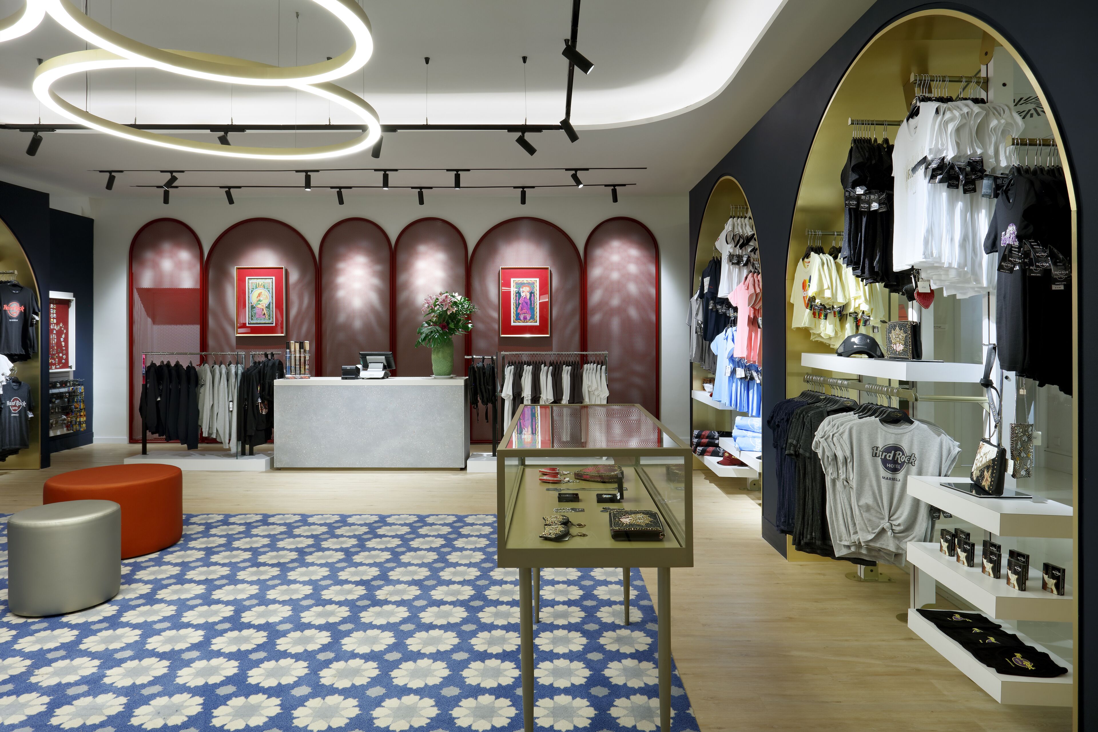 Una tienda moderna con una mesa de exhibición central, percheros y una alfombra estampada.
