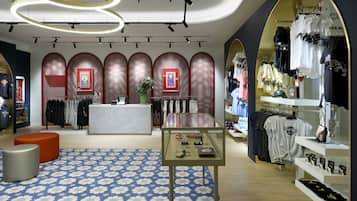 Una tienda moderna con una mesa de exhibición central, percheros y una alfombra estampada.
