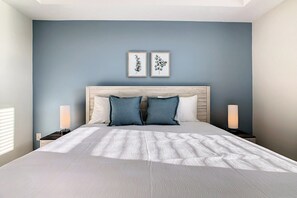 A bed with a white textured bedspread, two pillows, a wooden headboard, and two bedside lamps.