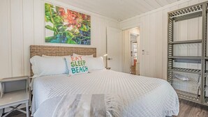 A bedroom with a bed, a painting, and a built-in shelving unit.