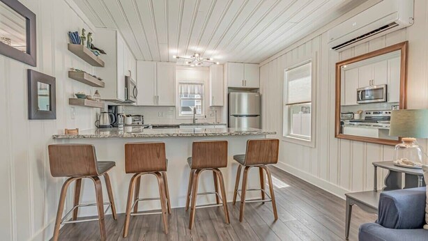 A modern kitchen with a central island, bar stools, and a dining area with a blue sofa.