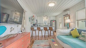 A compact living space with a kitchenette, a dining area with four chairs, a sofa with cushions, and a small table. - Coconut Flats Duplex- Upstairs- (North Myrtle Beach)