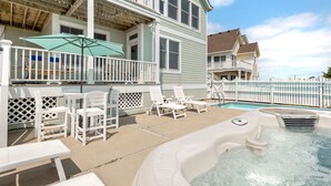 A pool area with lounge chairs and a hot tub, surrounded by a wooden deck and a white fence. - Beachin Up With The Jones's: Private Pool, Dogs OK (Corolla)