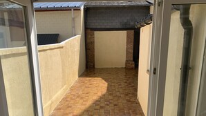 Un petit patio extérieur avec un sol en briques et un toit recouvert de tuiles.