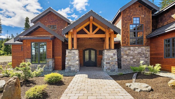 A log cabin with a stone foundation, a central entrance with a decorative door, and a brick pathway leading to the entrance. - Private Indoor Pool! The Northwest's most unique vacation experience!! (Cle Elum)