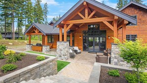 A modern log cabin with a stone foundation, a covered patio, and a large glass door entrance. - Private Indoor Pool! The Northwest's most unique vacation experience!! (Cle Elum)