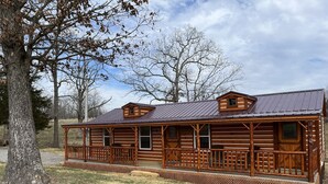 A log cabin with a porch, a small attic window, and a metal roof. - Griffis Game Hunting and/or Getaway (West Union)
