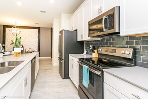 Una cucina moderna con elettrodomestici in acciaio inossidabile, mobili bianchi e una parete backsplash piastrellata.
