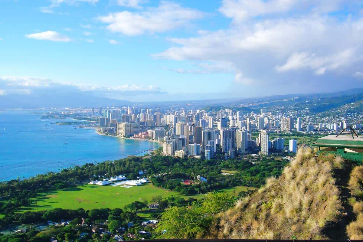 A coastal cityscape with high-rise buildings, a marina, and a green park area.