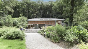 Ein Gebäude mit Holzfassade, einer Schotterauffahrt und einem Garten mit verschiedenen Pflanzen und Sträuchern.