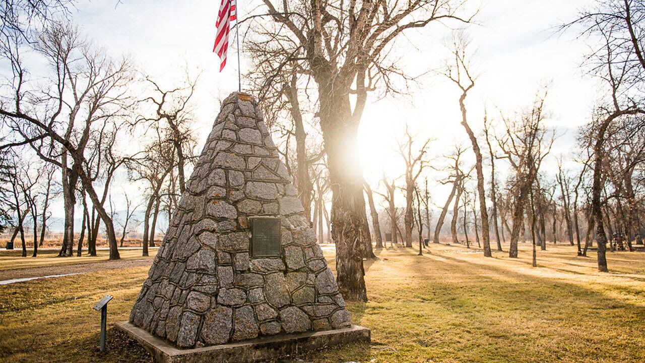 Een stenen monument met een Amerikaanse vlag, omringd door bladerloze bomen in een park.