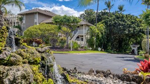 Un quartier résidentiel avec une maison à deux étages, une petite cascade et une végétation luxuriante.