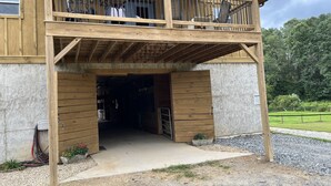 A wooden building with a balcony, a covered entrance, and a gravel driveway.