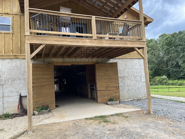 A wooden building with a balcony, a covered entrance, and a gravel driveway.