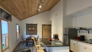A modern kitchen with a central island, white cabinetry, and a wooden ceiling.