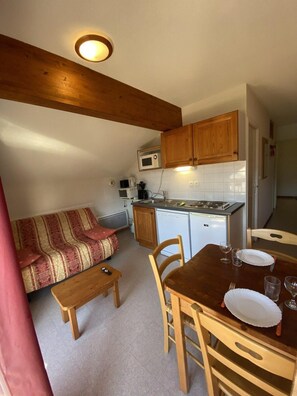 A compact kitchen with wooden cabinets, a microwave, and a dishwasher.