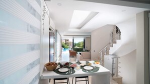 Une cuisine moderne avec un coin repas, un escalier et une vue sur l’extérieur.