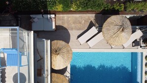 Vue aérienne d’un espace piscine avec des chaises longues et des parasols.
