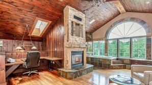 A spacious room with a stone fireplace, wooden ceiling, and large windows offering a view of the outdoors. - Large cottage with Water front, Heated Pool, sauna, 4 family rooms (Fergus)