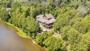 An aerial view of a house surrounded by dense forest, with a river to the left. - Large cottage with Water front, Heated Pool, sauna, 4 family rooms (Fergus)