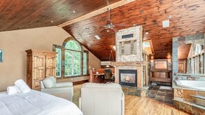 A spacious room with a wooden ceiling, a stone fireplace, a large window, and a cozy seating area. - Large cottage with Water front, Heated Pool, sauna, 4 family rooms (Fergus)