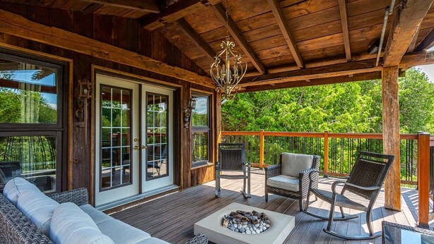 A wooden deck with wicker furniture, a fire pit, and a chandelier. - Large cottage with Water front, Heated Pool, sauna, 4 family rooms (Fergus)
