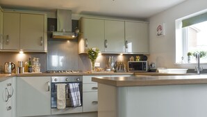 A modern kitchen with a central island, stainless steel appliances, and a window providing natural light. - Boasting a private garden, stunning views and ample parking. (St. Michael&rsquo;s on Wyre)
