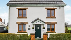 A two-story white house with a green door, four windows with wooden frames, and a chimney. - Boasting a private garden, stunning views and ample parking. (St. Michael&rsquo;s on Wyre)