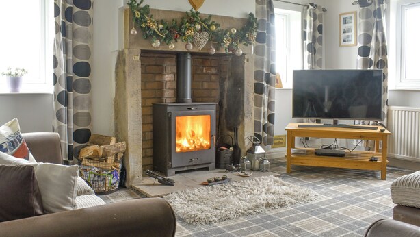 A cozy living room with a fireplace, a television on a wooden stand, and a plaid carpet. - Boasting a private garden, stunning views and ample parking. (St. Michael&rsquo;s on Wyre)