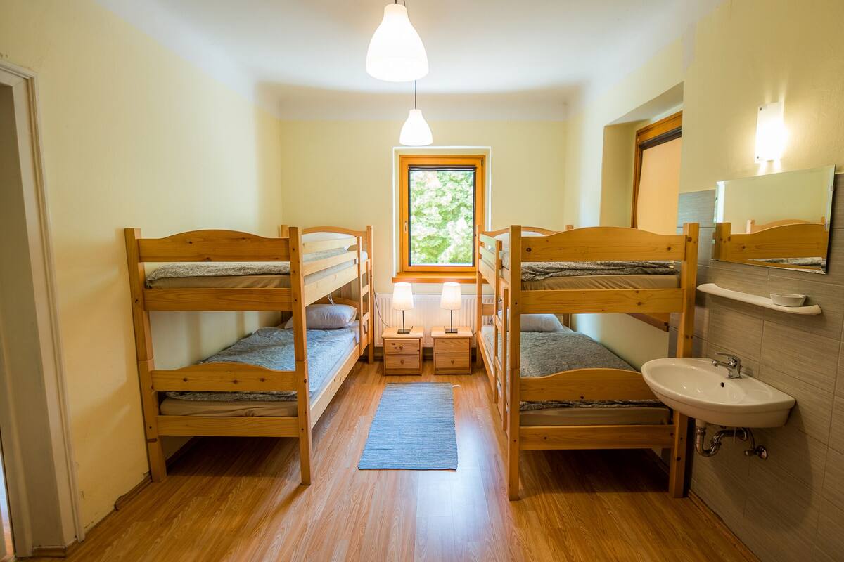 A compact room with two bunk beds, a small window, a sink, and a mirror.