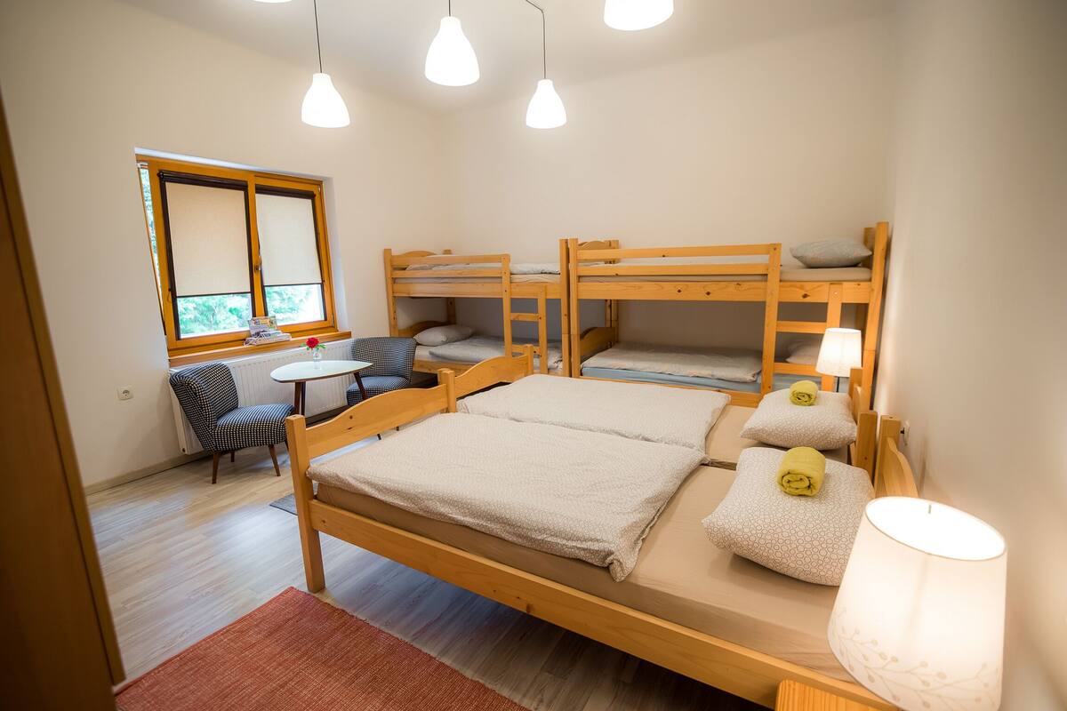 A room with bunk beds, a desk, a chair, and a window.