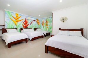 A hotel room with three wooden beds, white bedding, and a mural of tropical plants on the wall. - Hotel Jardines Evans By Geh Suites (Mompos)