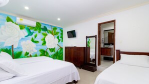 Habitación de hotel con dos camas, un gran mural floral en la pared, un televisor y un armario de madera.