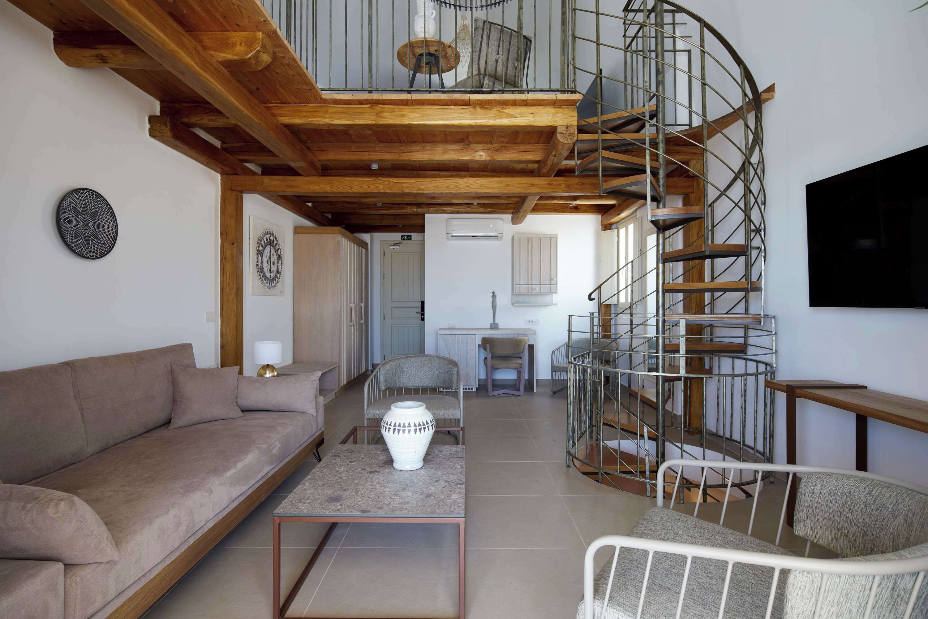 Un salon moderne avec un canapé, une table basse, un fauteuil et un escalier en colimaçon.