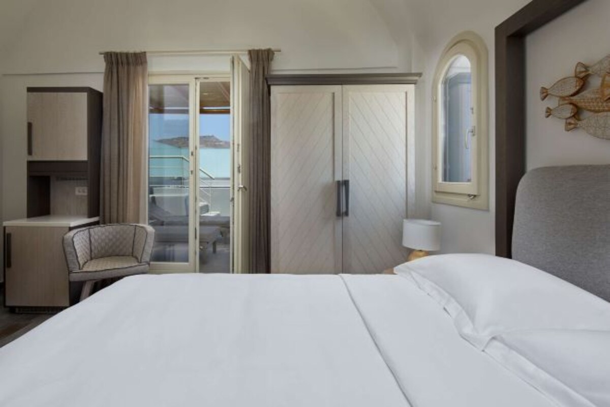 Een hotelkamer met een bed, een bureau, een stoel, een raam en een deur.