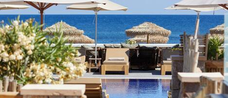 Ein Poolbereich mit Liegestühlen und Sonnenschirmen, der zu einem Pool mit freiem Blick auf das Meer führt.