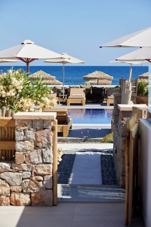 Ein Poolbereich mit Liegestühlen und Sonnenschirmen, der zu einem Pool mit freiem Blick auf das Meer führt.