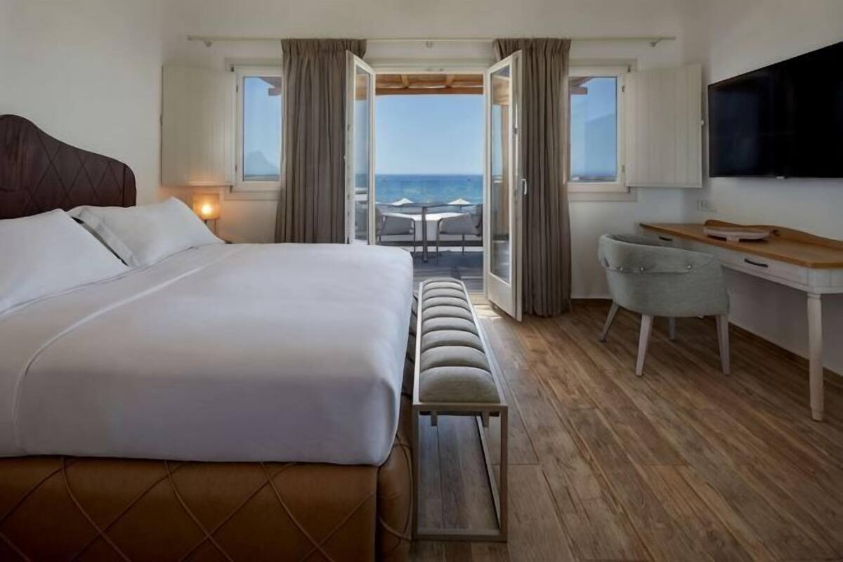 Une chambre d’hôtel équipée d’un lit, d’un bureau, d’une chaise, d’un banc et d’une télévision.