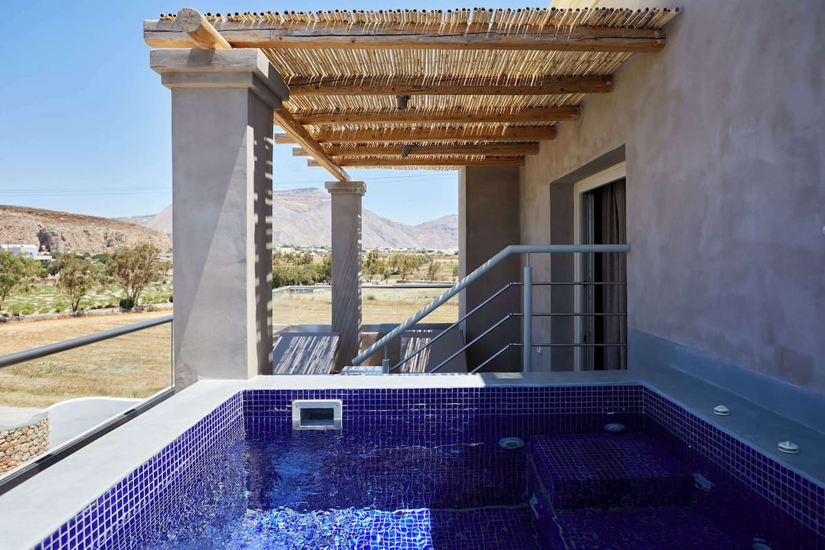 Un espace bien-être comprenant un jacuzzi, une pergola en bois et une vue sur le paysage environnant.