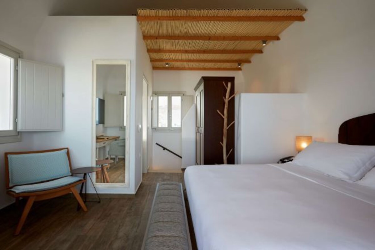 Een moderne hotelkamer met een bed, een stoel, een bureau en een garderobe.