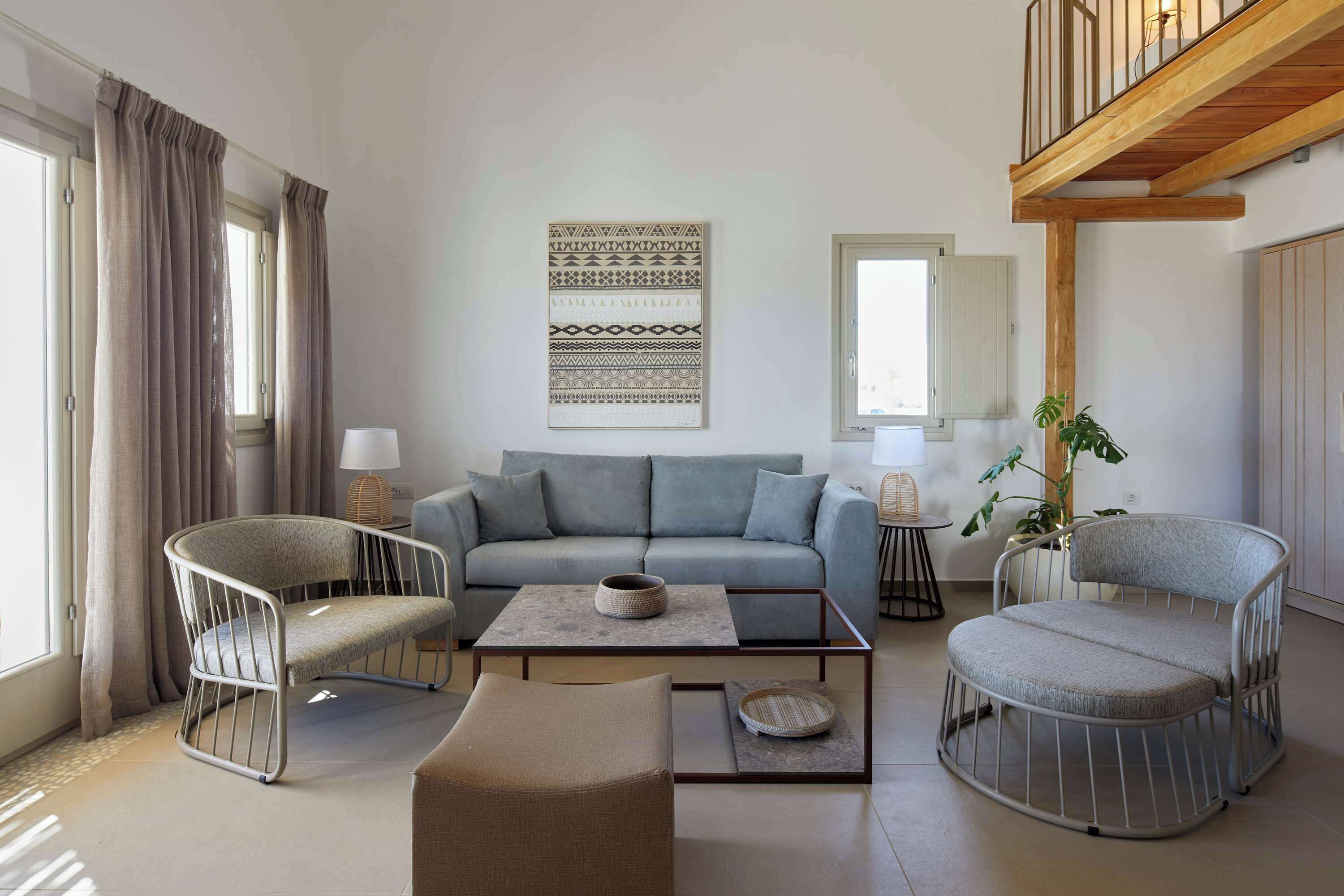A modern living room with a grey sofa, two metal-framed chairs, a coffee table, and a wooden ceiling.