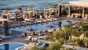 Zwembadgedeelte van een resort met ligbedden, een cabana en uitzicht op de oceaan.