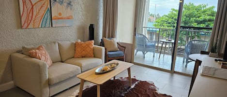 Una sala de estar con un sofá, una mesa de centro y vistas al exterior a través de una puerta corrediza de vidrio.