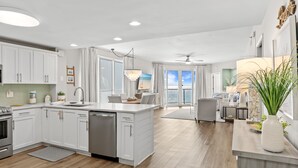 A modern kitchen with white cabinetry, a central island, and a dining area with a view.