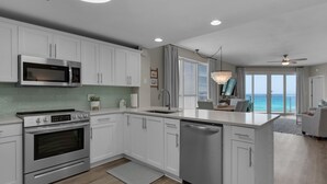 A modern kitchen with stainless steel appliances, white cabinetry, and a large island.