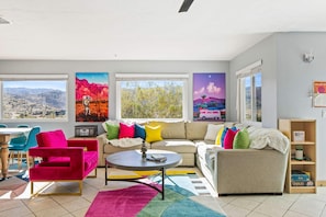 Un salon moderne avec un canapé, des fauteuils, une table basse et des œuvres d’art colorées accrochées aux murs.